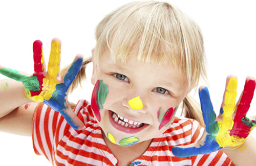 A smiling child showing off colourful painted hands at Barbies Footsteps nursery